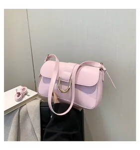 Close-up of pink square handbag featuring golden U-shaped clasp and detachable strap