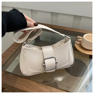 Close-up of cream white shoulder bag with a silver square buckle and adjustable strap