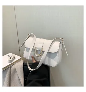 Detailed close-up of a white leather shoulder bag with a stylish gold horseshoe metal buckle