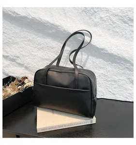 Détail d'un grand sac cabas noir minimaliste avec de longues anses et poche avant