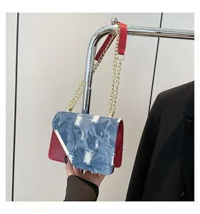 Detail of blue denim and red leather patchwork bag with gold chain strap design