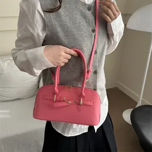 Vintage roze handtas met gouden hardware en schouderband gedragen door een model