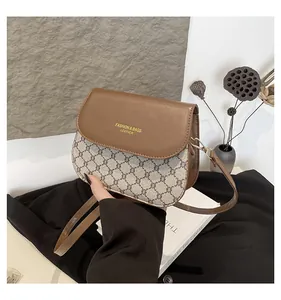 Close-up of vintage brown leather flap with gold lettering on a checkered crossbody bag