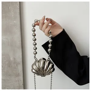 Close-up of a silver shell-shaped evening clutch bag with a metallic bead handle