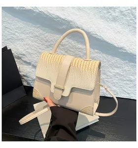 Detail shot of cream animal-textured leather handbag with golden metallic clasp
