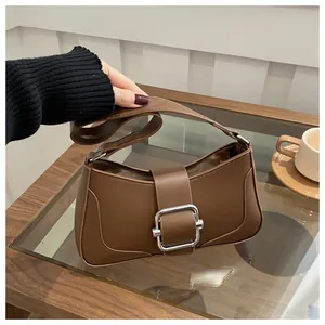 Close-up of stylish brown faux leather handbag with silver square buckle and smooth texture
