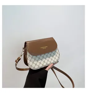 Detailed shot of brown leather flap with gold logo and adjustable shoulder strap buckle