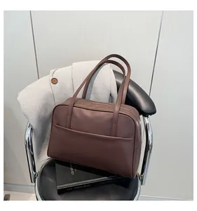 Détail du sac cabas marron foncé mat avec coutures et fermeture éclair sur chaise noire