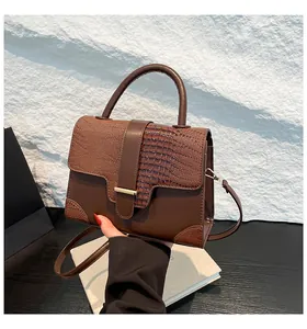 Macro detail of brown crocodile embossed leather and gold metal trim on handbag