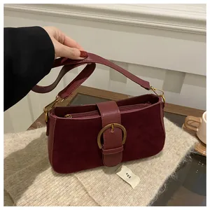 Gros plan du sac bandoulière en daim bordeaux avec boucle en métal doré vintage