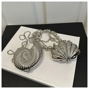 Detailed macro view of mirror-finish silver metallic shell-shaped evening clutch bags