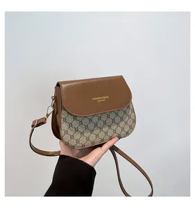 Detail of vintage style crossbody bag with leather flap and monogram canvas texture