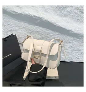 Detail of creamy white leather handbag with golden U-shaped buckle and adjustable strap