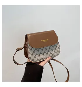 Close-up of contrast checkered flap bag with golden buckle and leather strap