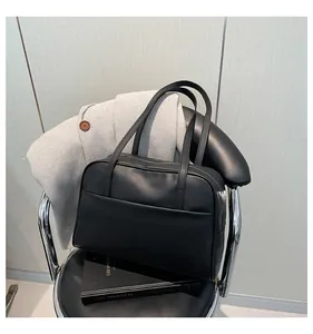 Détail d'un sac Boston noir sur une chaise en cuir avec une esthétique de bureau élégante