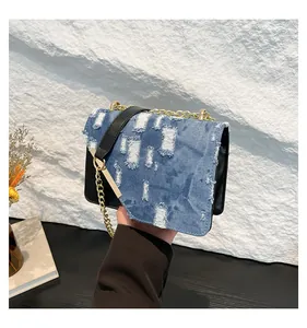Close-up of distressed blue denim chain bag with gold metal trim and leather panels