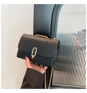 Détail de la texture tressée et du cuir embossé crocodile sur un sac à chaîne noir
