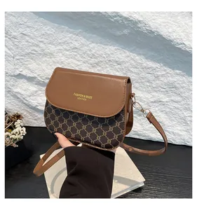 Detail of contrast plaid saddle bag featuring brown leather trim and golden hardware