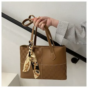 Close-up of brown tote bag with checkered texture and silk scarf handle detail