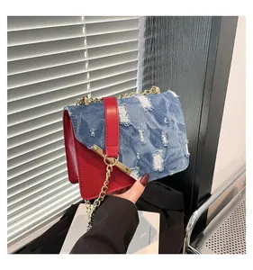 Detail of color-block shoulder bag with blue denim flap and red leather side panels