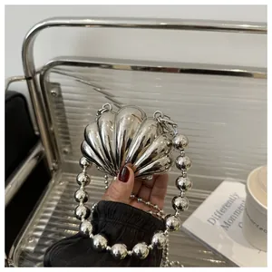 Silver shell-shaped evening clutch bag with metallic bead handle on a stylish background
