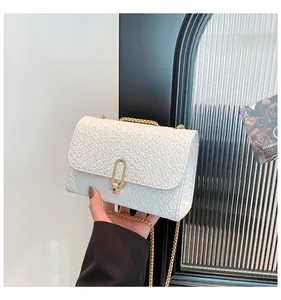 Détail du sac carré blanc à motif tissé avec fermoir doré et bandoulière chaîne