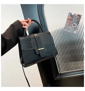 Close-up of black crocodile texture handbag with gold hardware and elegant stitching