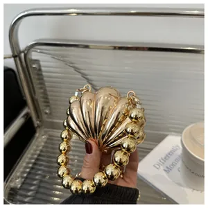 Detail view of a shell-shaped gold evening clutch bag with beaded handle and metallic finish