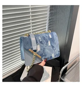 Detail of blue denim patchwork bag featuring vintage distressed texture and golden chain strap