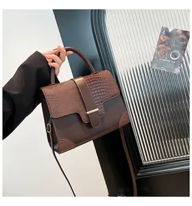 Detailed close-up of dark brown crocodile embossed leather texture and gold metal buckle