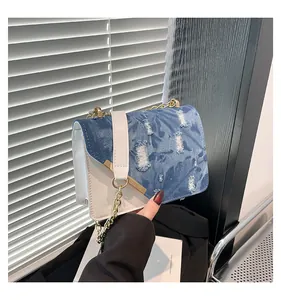 Detail of blue denim and white leather patchwork handbag with gold chain strap