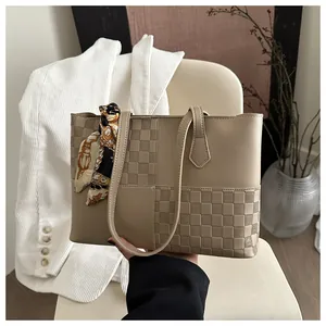 Detail of checkered patchwork tote bag featuring elegant silk scarf handle decoration