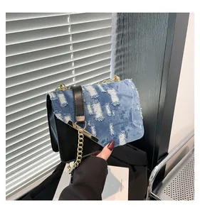 Detail of blue denim and black leather patchwork bag with gold chain strap detail