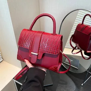 Deep red crocodile texture handbag with metal buckle and top handle in a lifestyle setting