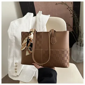 Detailed view of brown checkered tote bag with silk scarf on white chair