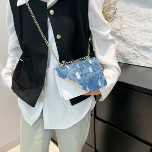 Blue denim and white leather patchwork crossbody bag with elegant gold chain strap
