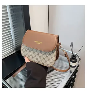 Detailed close-up of brown faux leather flap and gray geometric pattern on crossbody bag