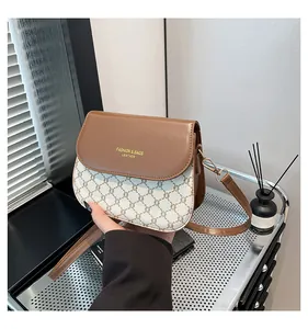 Detail of a brown leather flap and monogram crossbody bag with gold hardware accents
