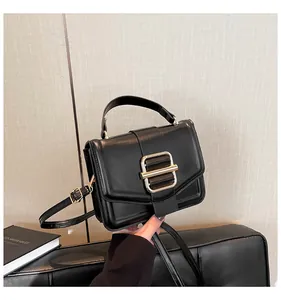 Detailed shot of a black leather square handbag with an elegant golden clasp on a sofa