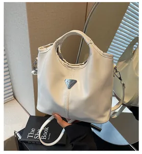 Detailed view of the cream leather tote bag featuring a triangle metal logo and handles