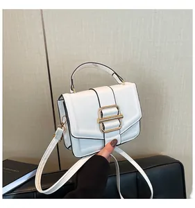 Detail of white leather handbag with gold square buckle and detachable shoulder strap