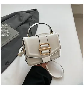 Detail of cream white leather handbag with gold buckle on a stylish office desk