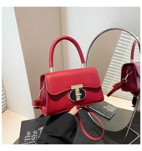 Macro shot of red leather mini square bag with golden T-shaped clasp and mirror reflection