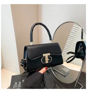 Close-up of black matte leather handbag with elegant gold T-lock and metal hardware