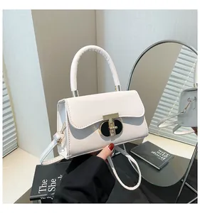 Detail of elegant cream leather handbag featuring a golden T-bar lock on minimalist table