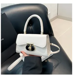 Detail of white leather handbag featuring gold wave-pattern lock and rounded top handle