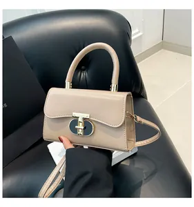 Close-up of a beige mini handbag featuring a gold T-bar lock and smooth leather texture
