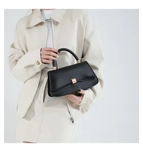 Dettaglio di borsa minimalista in pelle nera con chiusura rettangolare in metallo dorato
