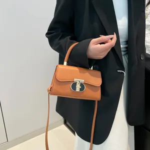 Elegant caramel brown leather crossbody bag with T-shaped buckle worn by model