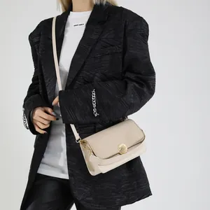Sac bandoulière beige contrasté avec boucle en métal sur modèle en blazer noir chic